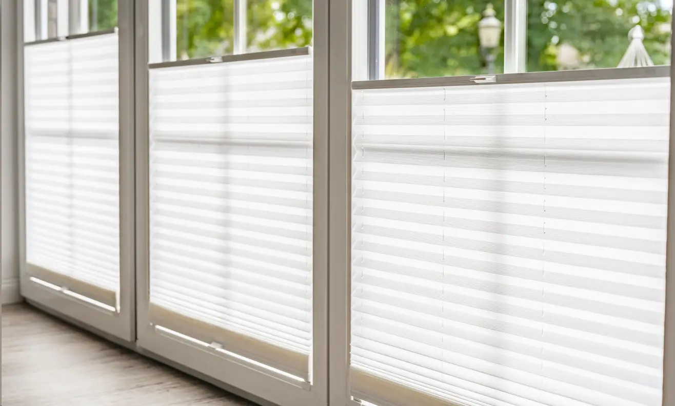 Weiße Plissees an einem Wohnzimmerfenster